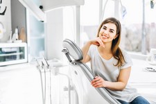 paziente-dentale-abbastanza-felice-e-sorridente-che-si-siede-nella-sedia-dentale-all-ufficio-dentale.jpg